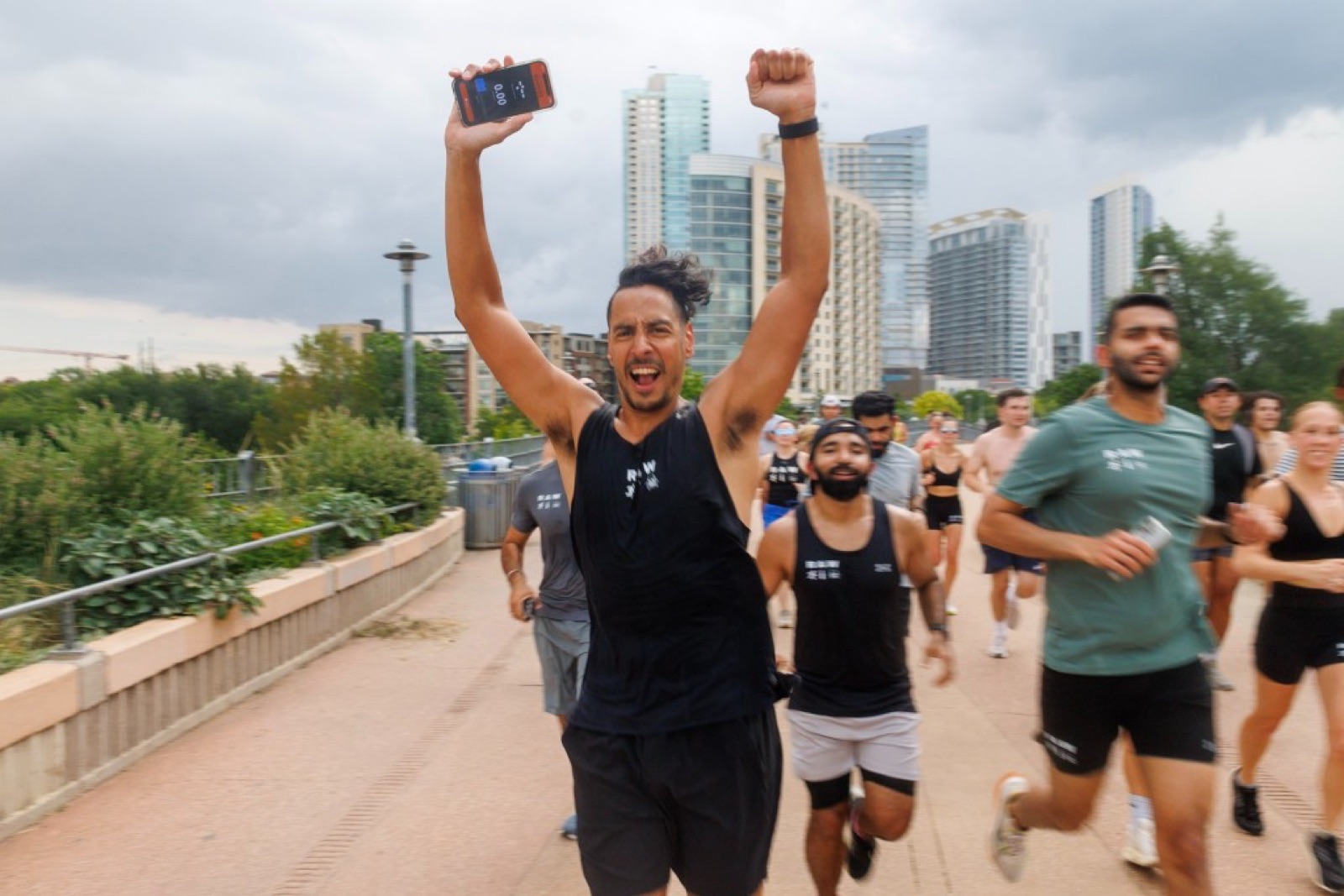 Runner celebrating with both arms raised on the boardwalk, downtown Austin skyline behind