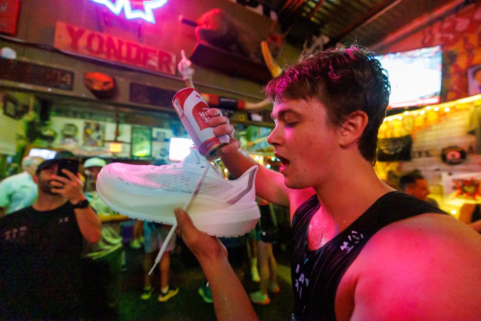 Crew member doing a shoey — sipping a beer out of a running shoe — at Mean Eyed Cat